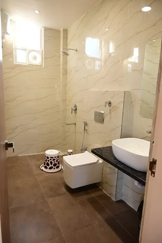 Clean bathroom with a marble-look wall, glass-screened shower, basin and wall-hung WC