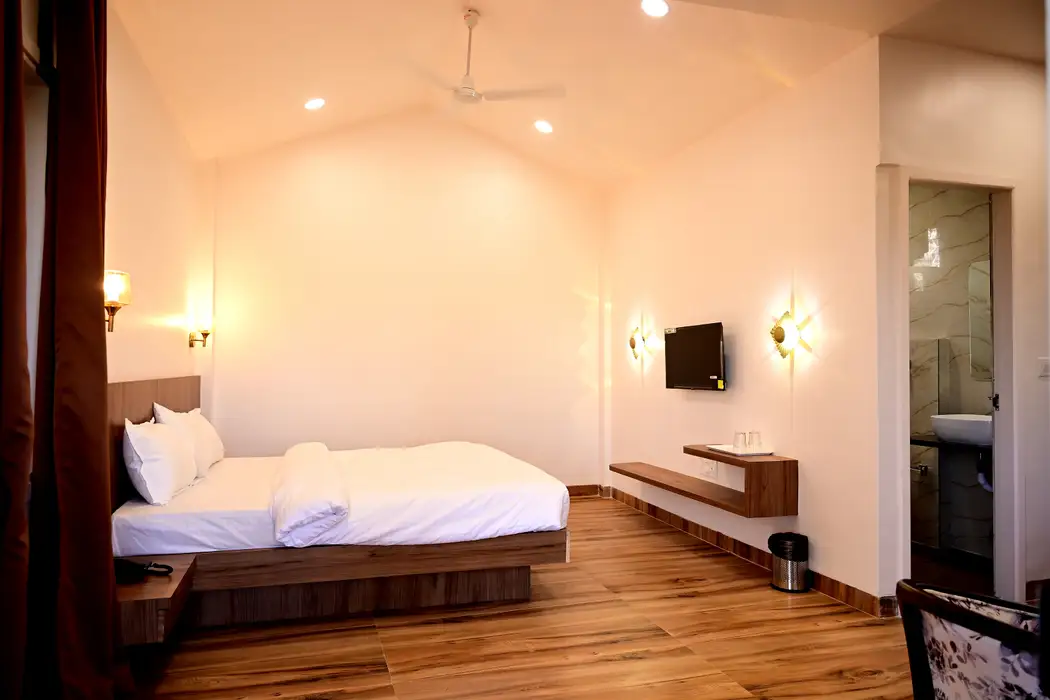 Cottage bedroom with a double bed, white linen, wooden floor, television and warm wall lamps
