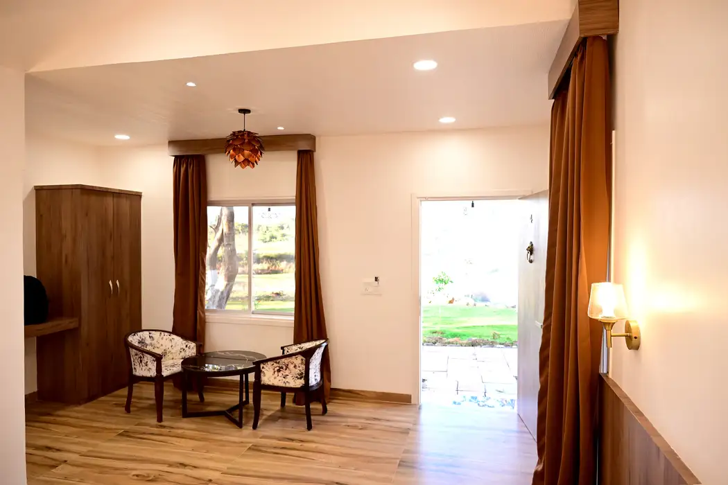 Cottage seating area with two chairs, a round table and a door opening onto the lawn