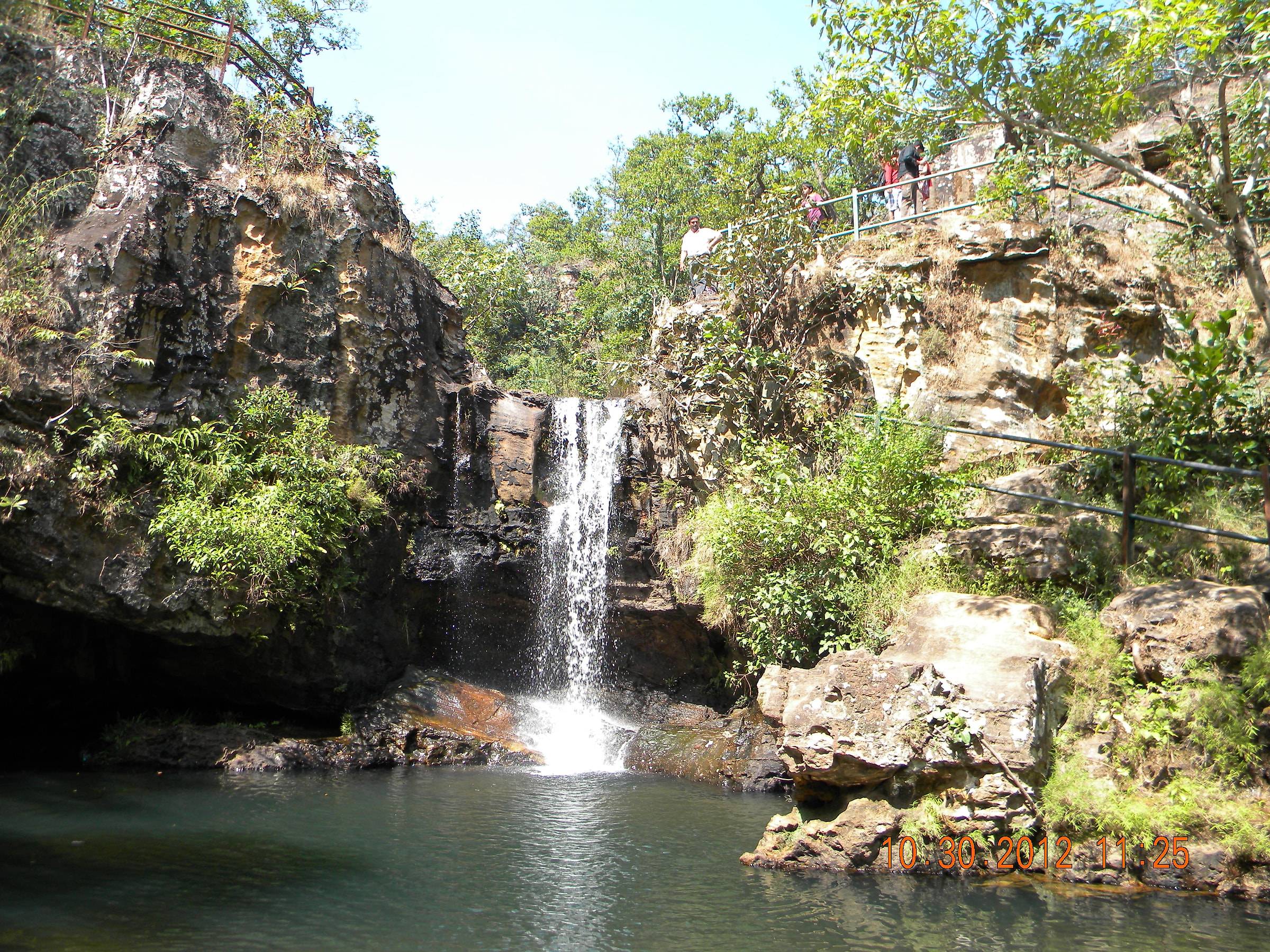 Bee Fall dropping into a green pool among sandstone cliffs