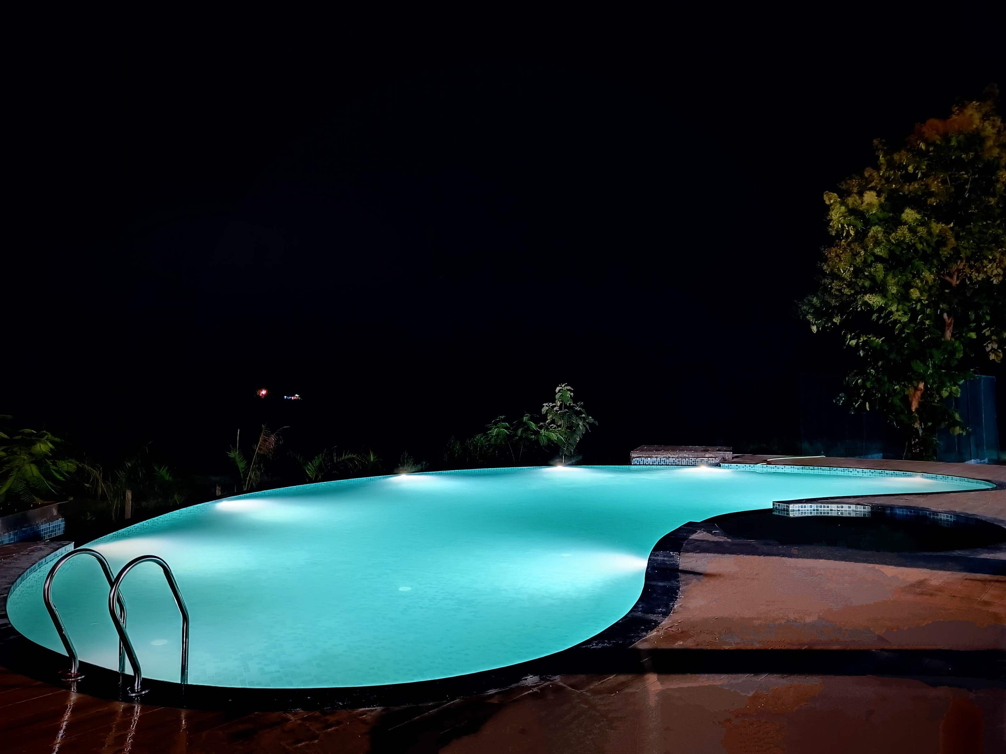 Swimming pool glowing turquoise under its lights at night